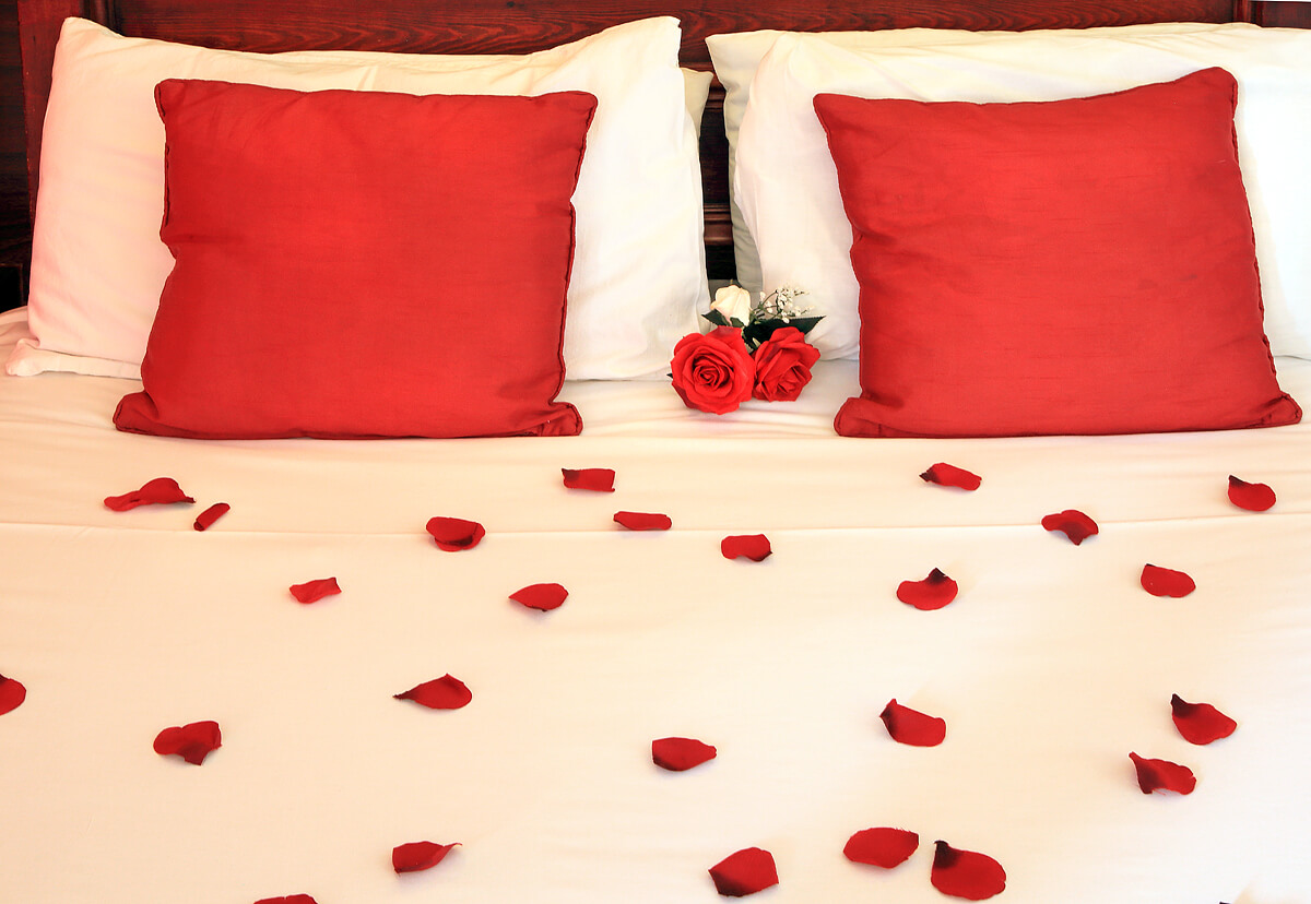 Honeymoon suite, scattered rose petals and roses laid upon ornate four poster bed